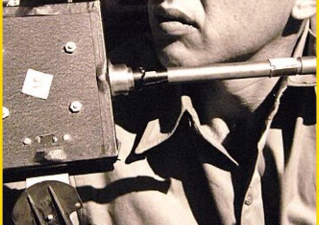 Black and white photograph from 1952 showing Mr. John R. Wren, Jr. inspecting the housing unit of a photo-electric cell, a key electronics device used by scientific observers to record fading light values of the sun during a solar eclipse.